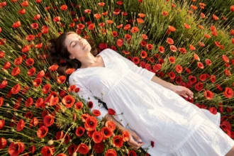 Femme endormie dans un champ de coquelicots rouges évoquant un rêve symbolique